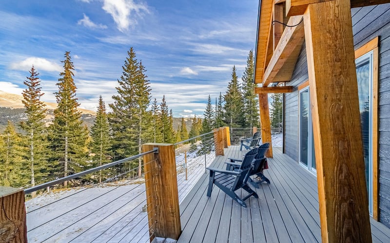 Deck with Adirondack chairs overlooking forest and mountain landscape